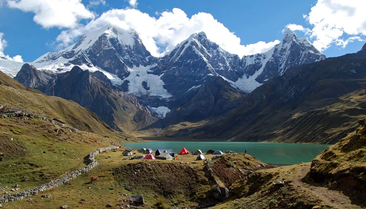Panoramic view of the Cordillera Huayhuash trekking circuit in Peru, featuring the snow-capped peaks of Yerupajá and Siula Grande and turquoise glacial lakes.
