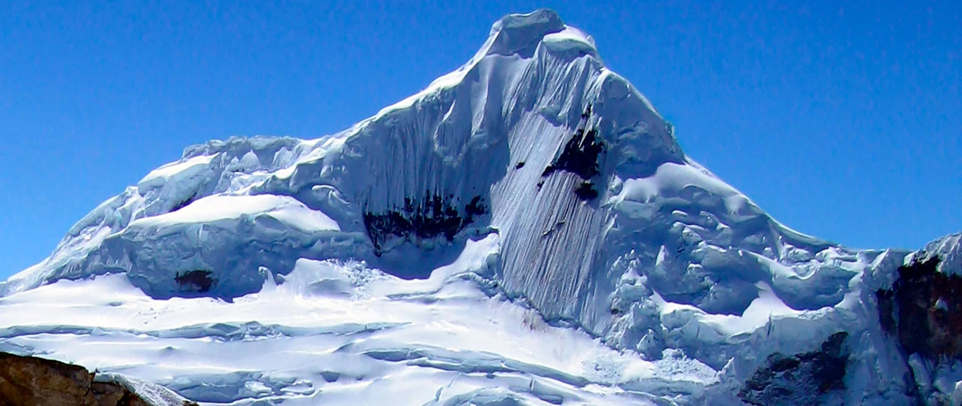 A mountaineer climbing the stunning and steep final summit ridge of Nevado Tocllaraju (6034m) in the Cordillera Blanca, Peru.
